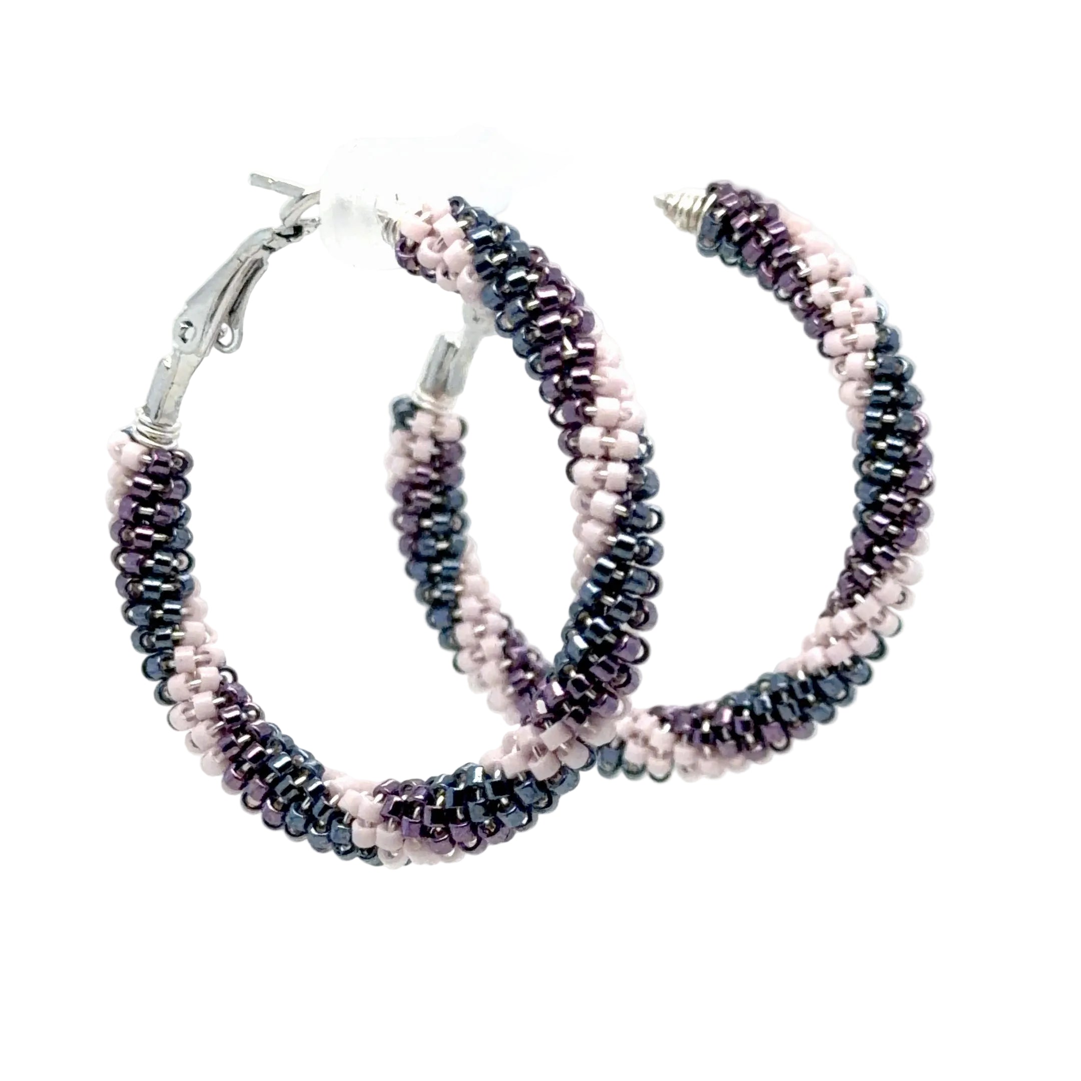 A pair of medium hoop earrings made from small seed beads in alternating rows of dark metallic silver and light pink, with silver-tone clasp closures, displayed on a white stand against a white background.