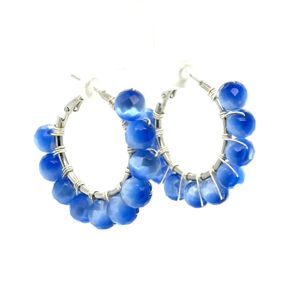 A pair of silver hoop earrings decorated with faceted blue beads wrapped in silver wire, shown against a plain white background.