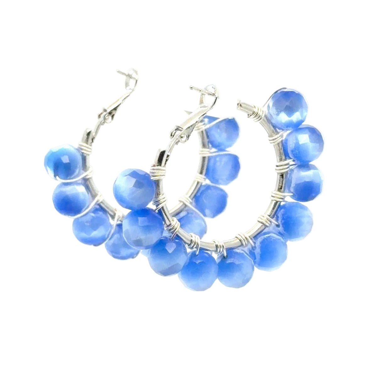 A pair of silver hoop earrings decorated with faceted blue beads wrapped in silver wire, shown on a plain white background.