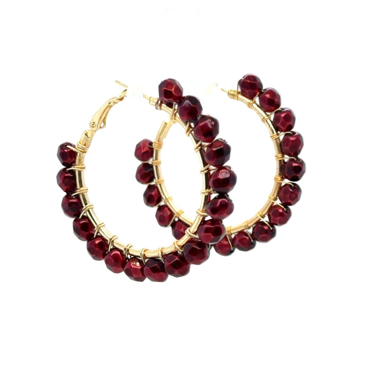 A pair of gold hoop earrings embellished with faceted dark red beads, displayed against a clean white background.