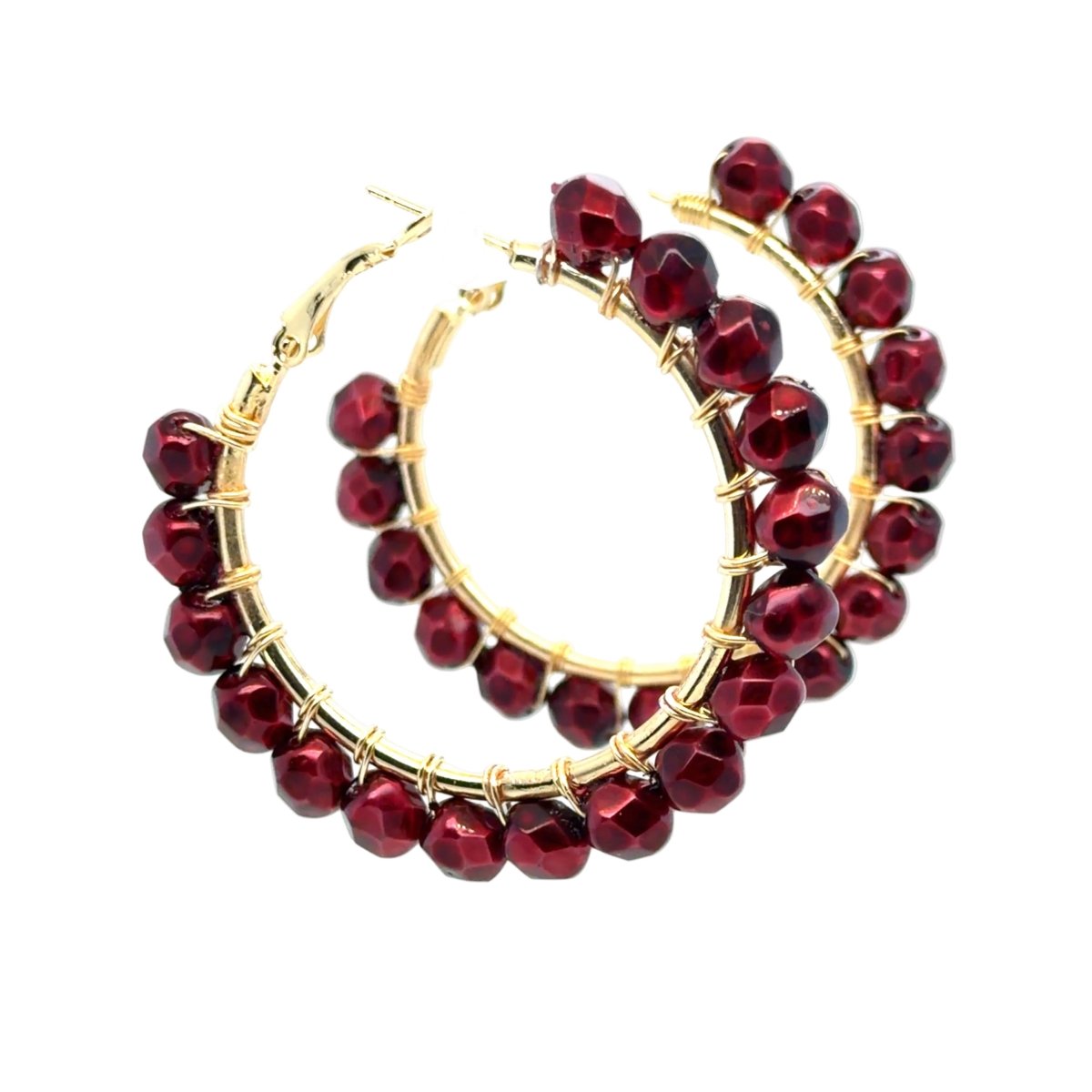 Gold hoop earrings adorned with faceted deep red beads, displayed on a clean white background.