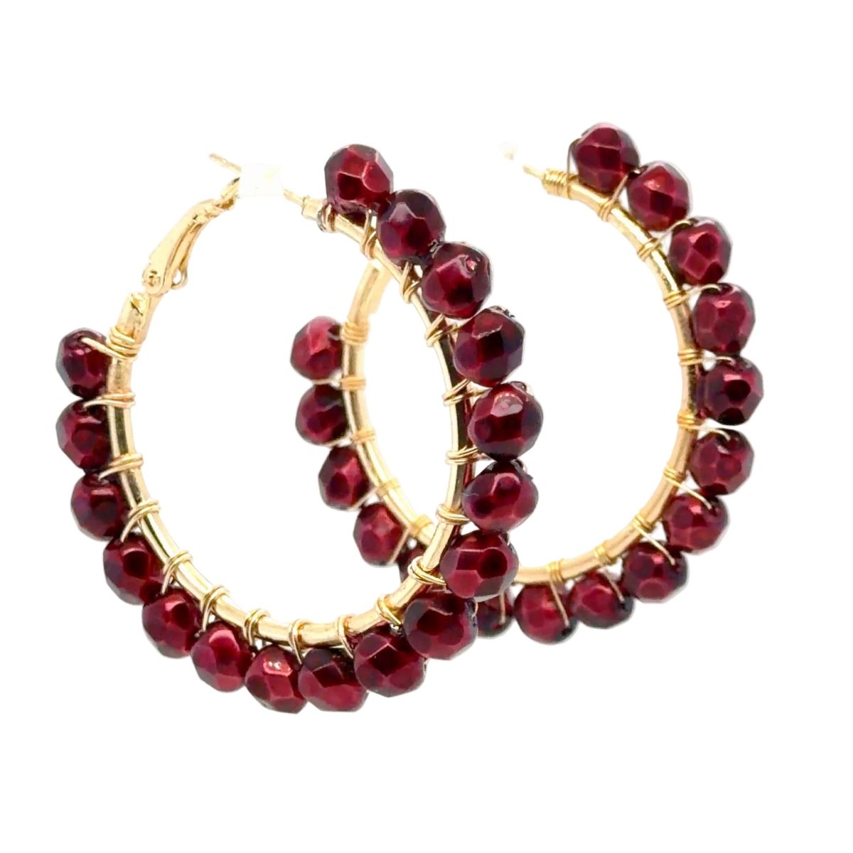 A pair of gold hoop earrings embellished with faceted deep red beads, shown against a plain white background.