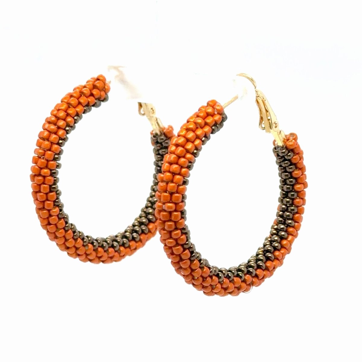Angled view of Maeven in Me burnt-orange and gunmetal beaded gold hoops showing the contrasting bead rows.