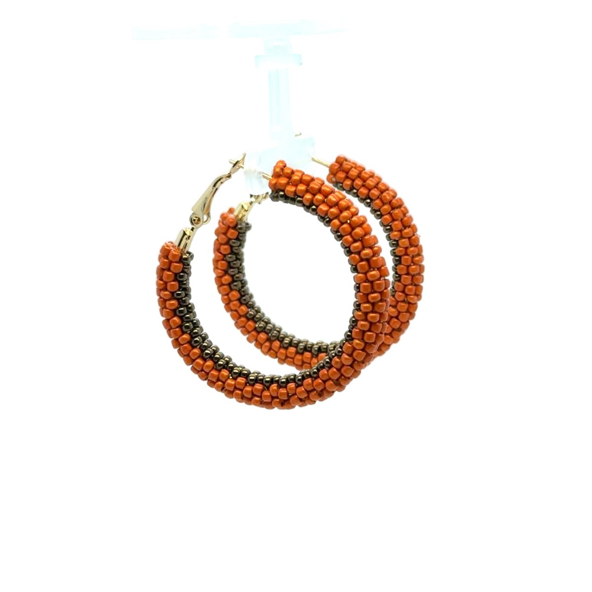 A pair of large hoop earrings made of orange and black seed beads, with gold-tone clasp closures, displayed on a clear plastic hanger against a white background.