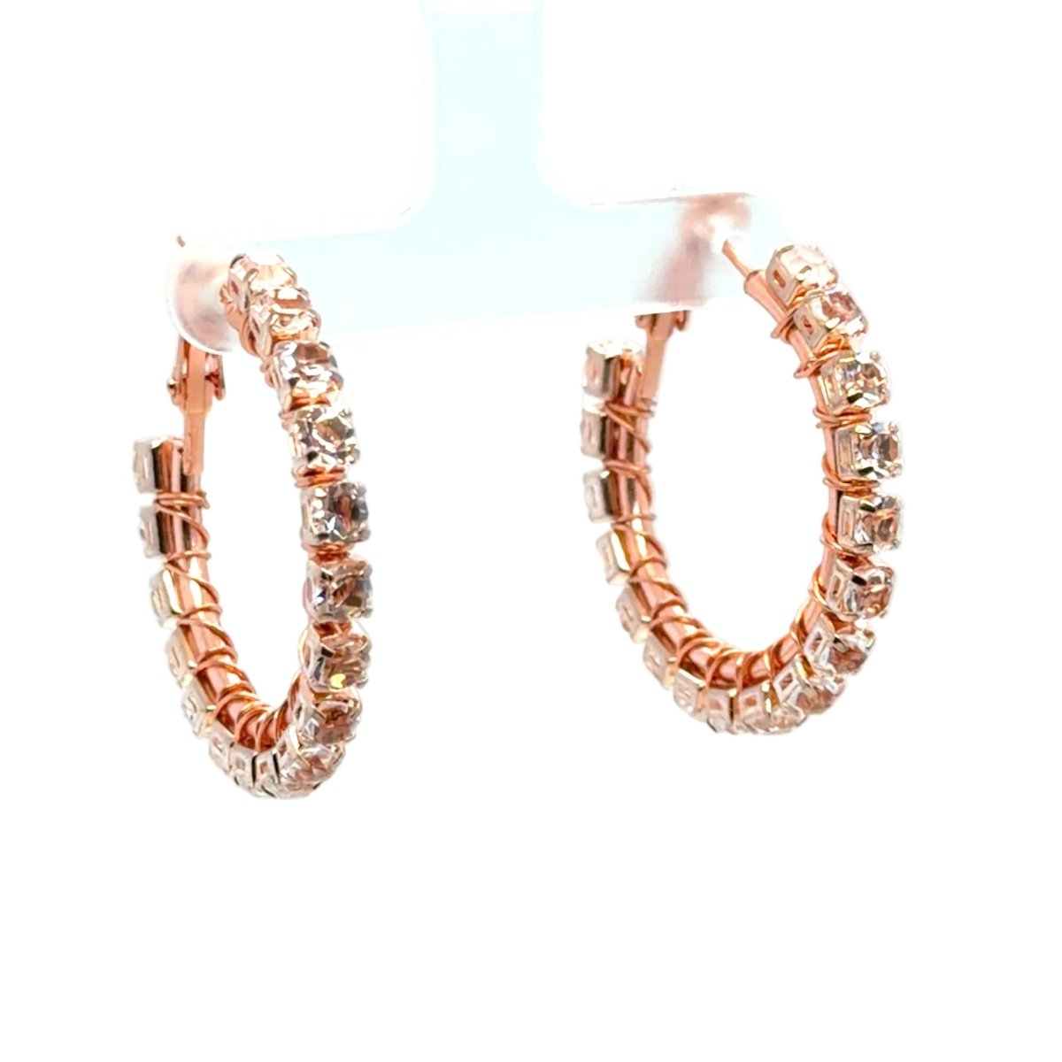 Rose gold hoop earrings adorned with clear rhinestones, displayed on a white jewelry stand against a white background.