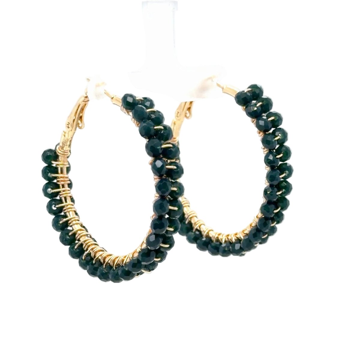 A pair of gold hoop earrings adorned with multiple rows of faceted dark green beads, displayed on a white hanger against a white background.