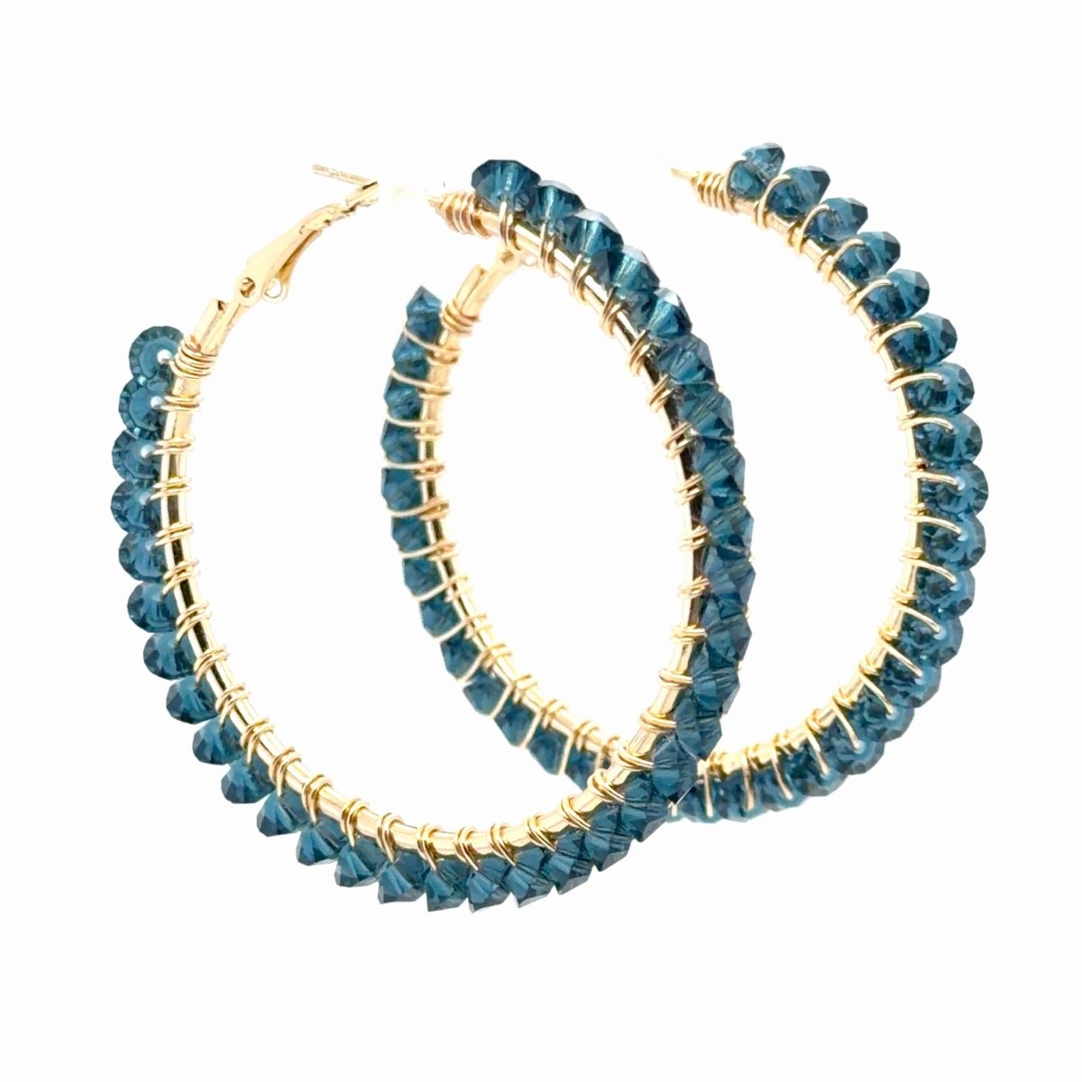 A pair of large gold hoop earrings embellished with faceted dark blue beads, shown on a plain white background.