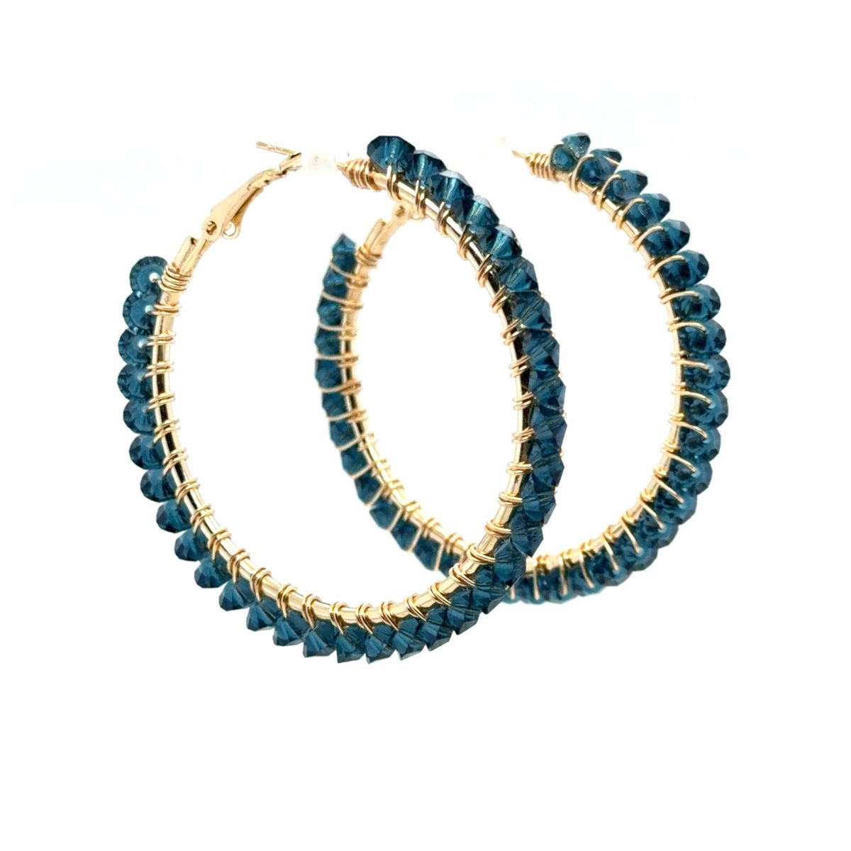 Angled view of Maeven in Me denim blue hoops with faceted beads and gold-colored wire wrapping.