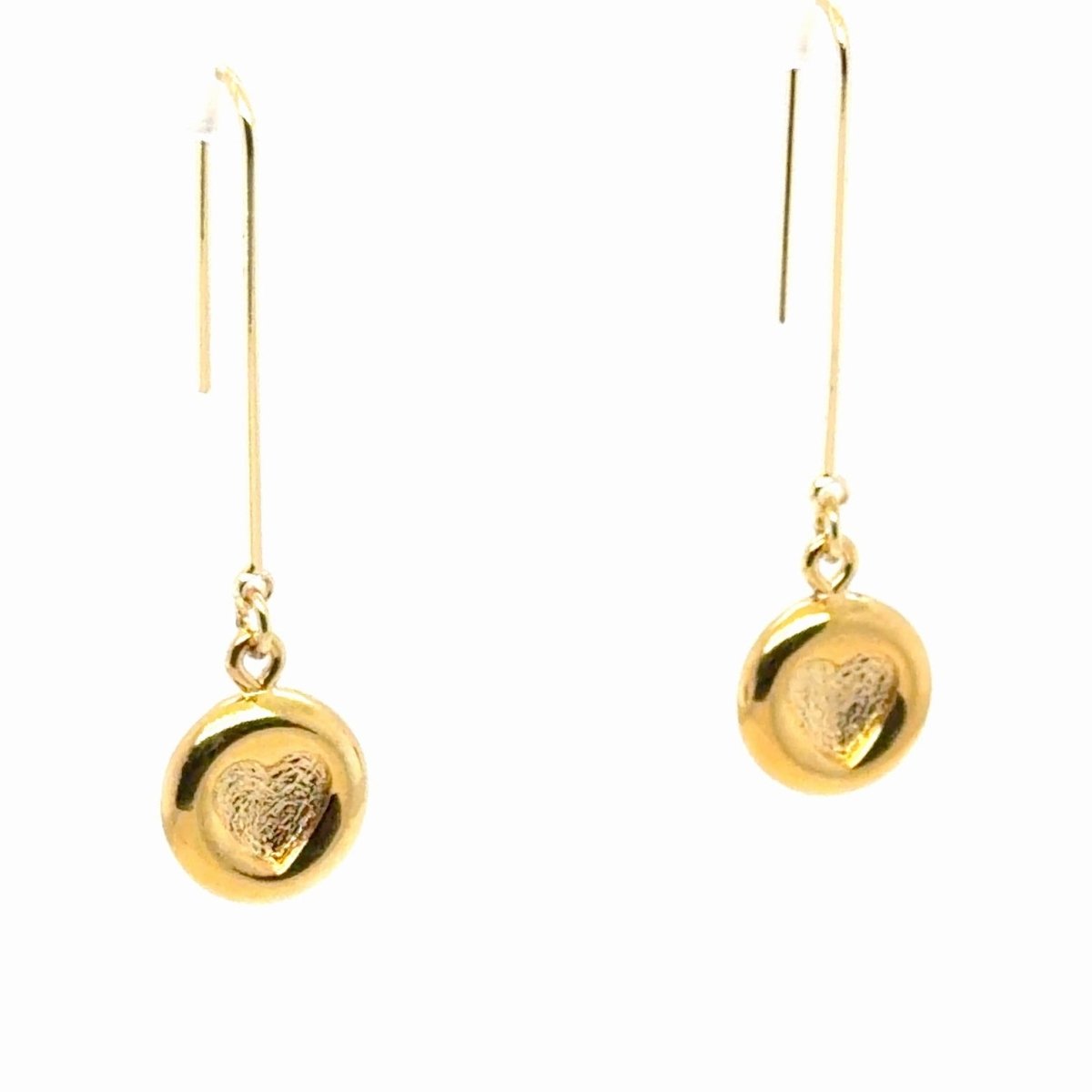 A pair of gold drop earrings with a textured heart design on a round disc, suspended from simple gold fishhook wires, shown against a plain white background.