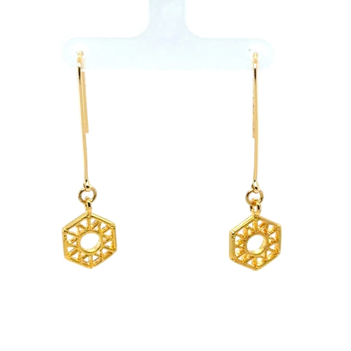 A pair of gold geometric drop earrings with a hexagonal filigree design, displayed on a white plastic jewelry hanger against a white background.