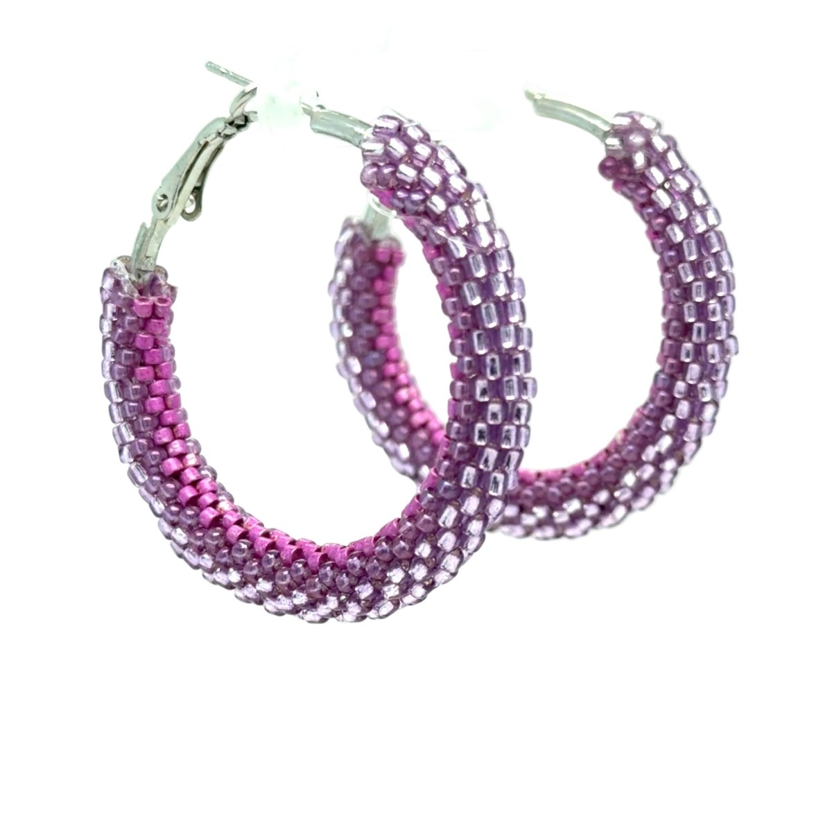 A pair of large hoop earrings made from tightly woven seed beads, transitioning in color from bright pink at the front to lavender-purple at the back, with silver-tone metal clasps on a white background.