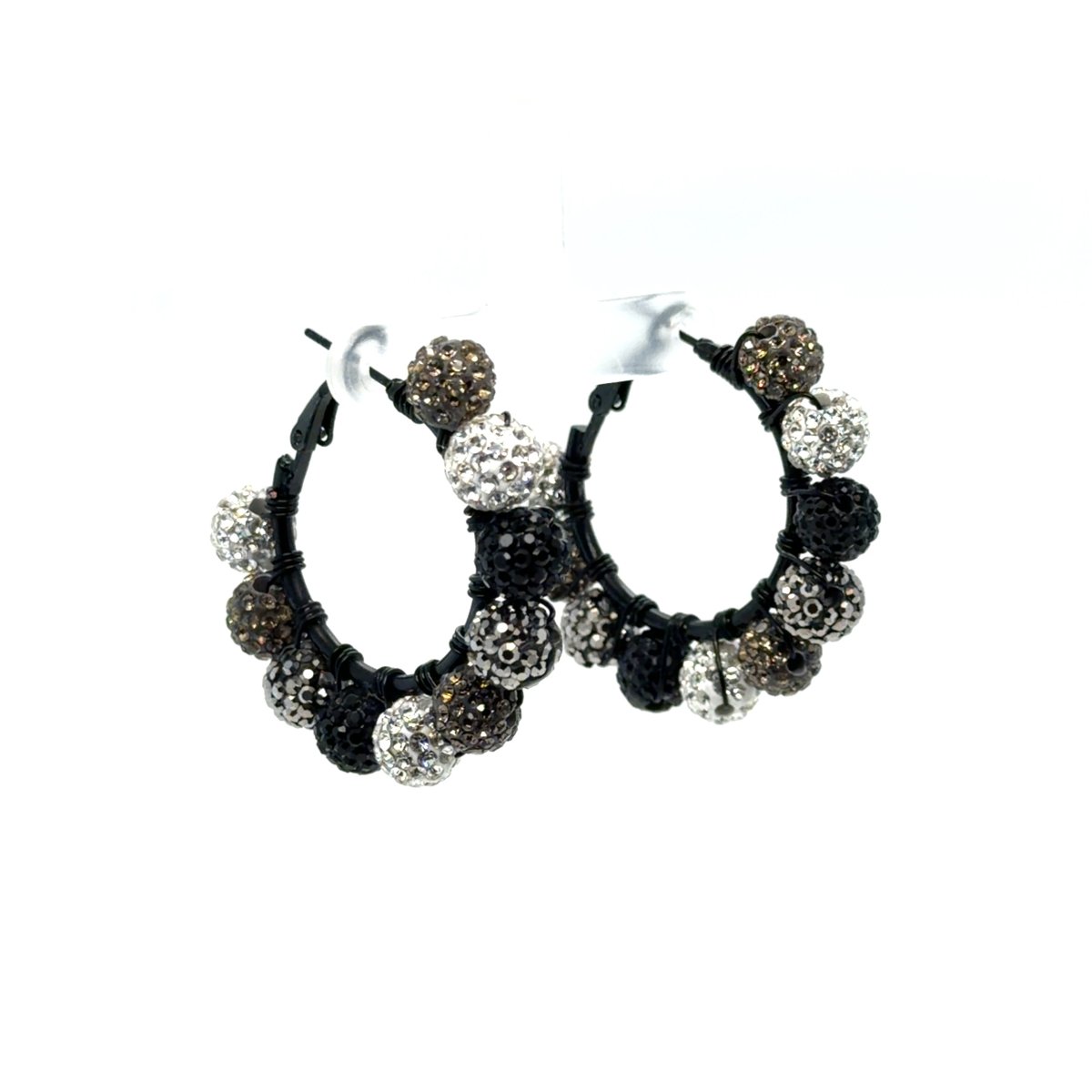 Maeven in Me black-finish hoops with silver, black, and smoky taupe rhinestone balls on a white display stand.