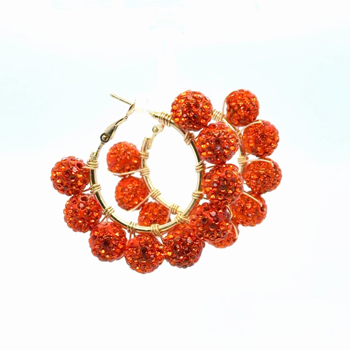 Close angled view of Maeven in Me orange rhinestone ball gold hoop earrings with wire wrapping and open hinged closures.