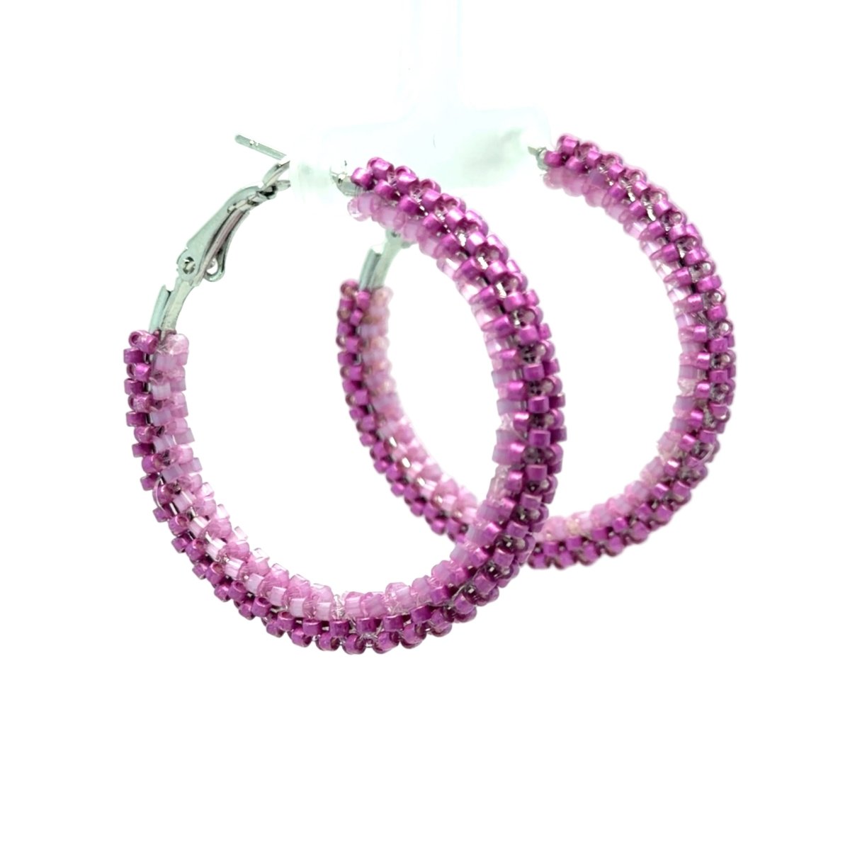 A pair of large hoop earrings made of pink faceted beads, featuring silver-tone metal clasps, displayed on a white plastic hanger against a white background.
