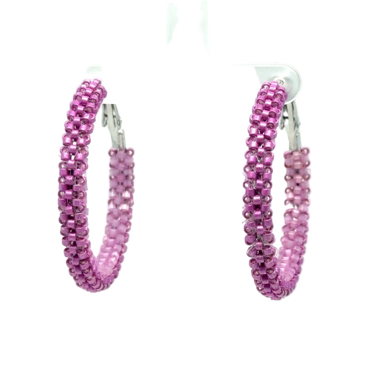 A pair of large hoop earrings made of tightly woven pink beads, hanging from a clear plastic display stand against a white background.
