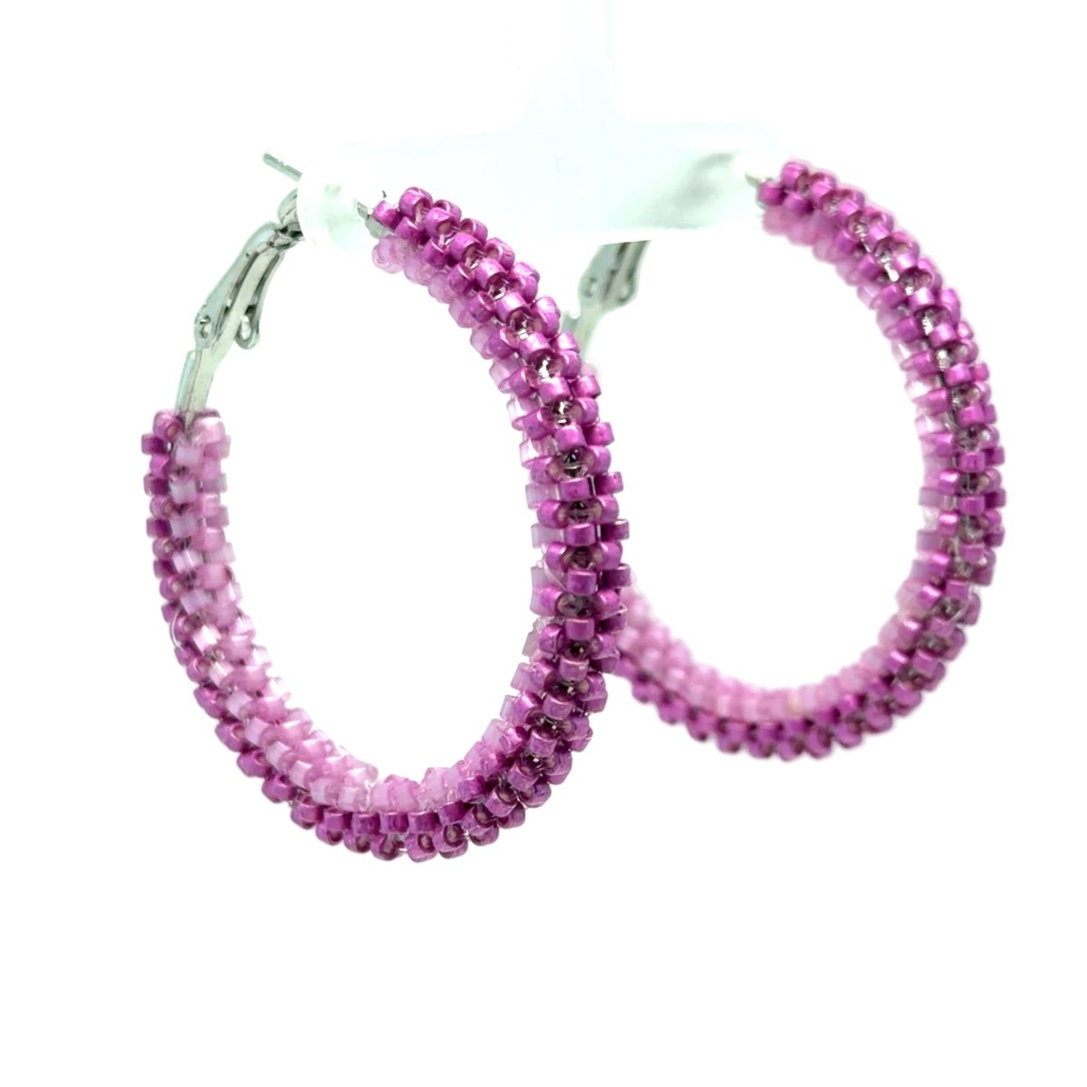 A pair of large hoop earrings made of small pink faceted beads, with silver-tone clasp backs, displayed on a white plastic hanger against a white background.